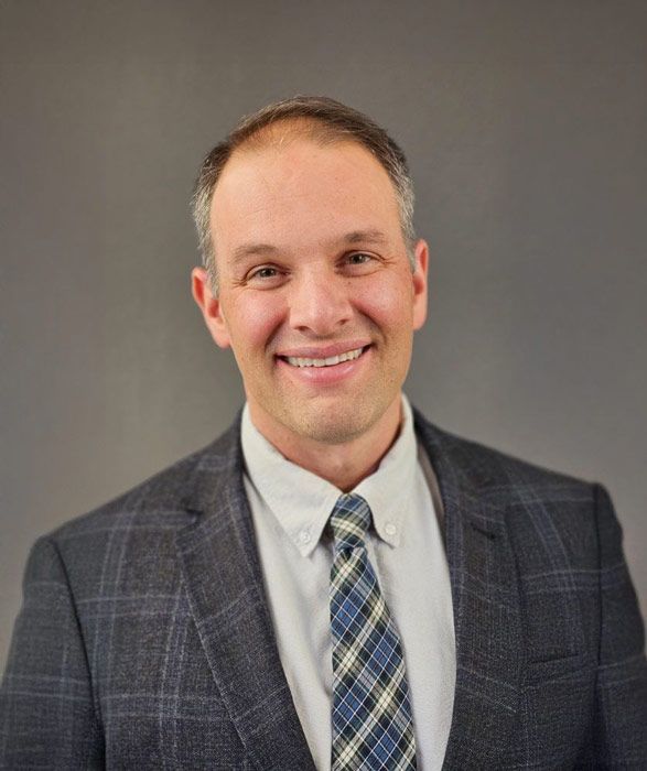 A man in a suit and tie is smiling for the camera.