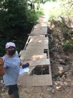 A woman wearing a mask is standing on a wooden bridge