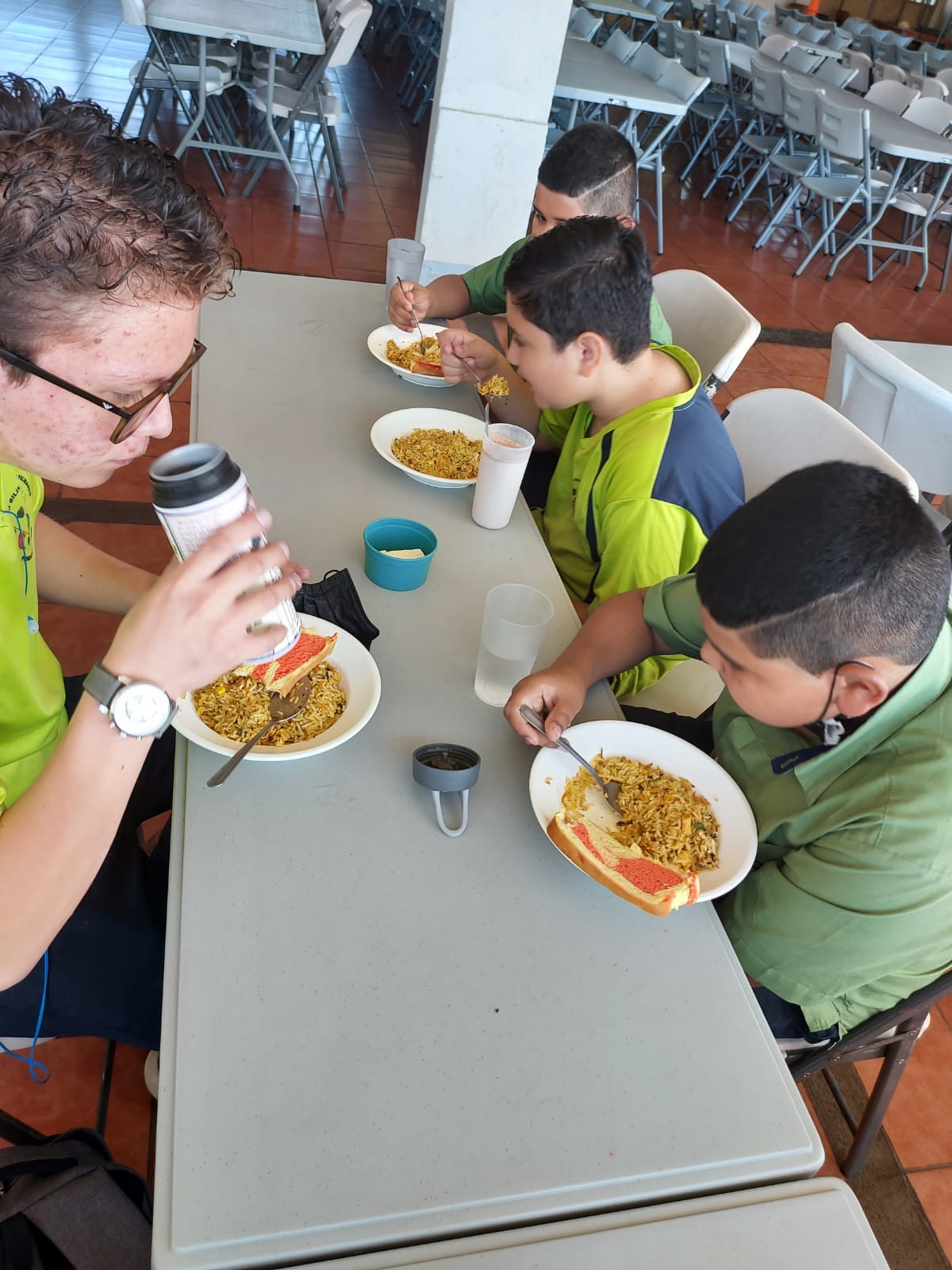 A group of young boys are sitting at a table eating food.