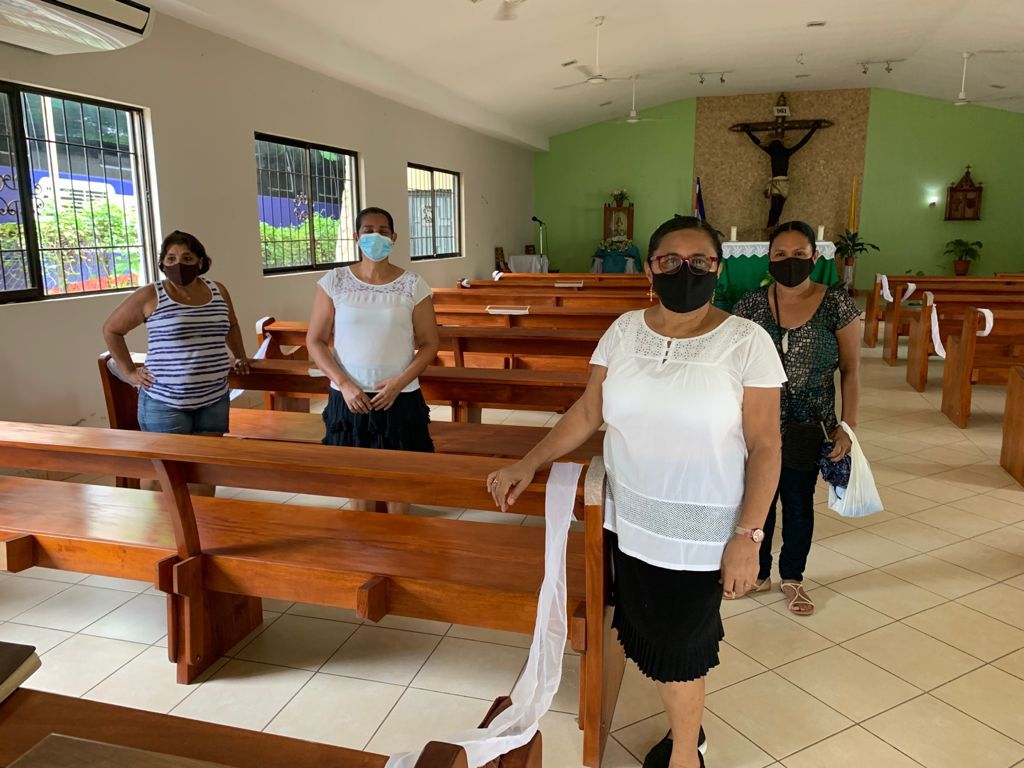 A group of women wearing face masks are standing in a church.