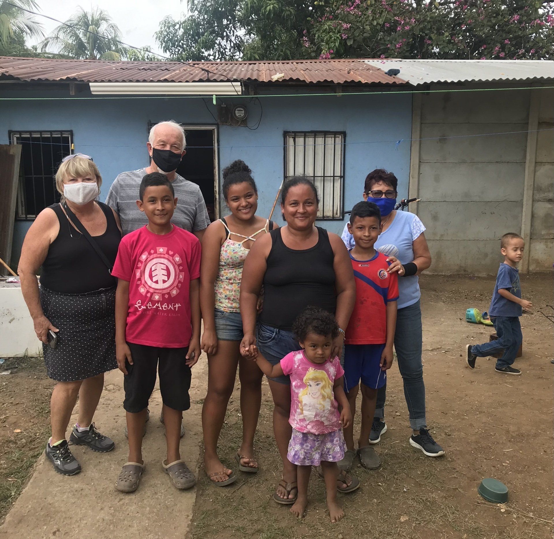 A group of people standing in front of a blue house