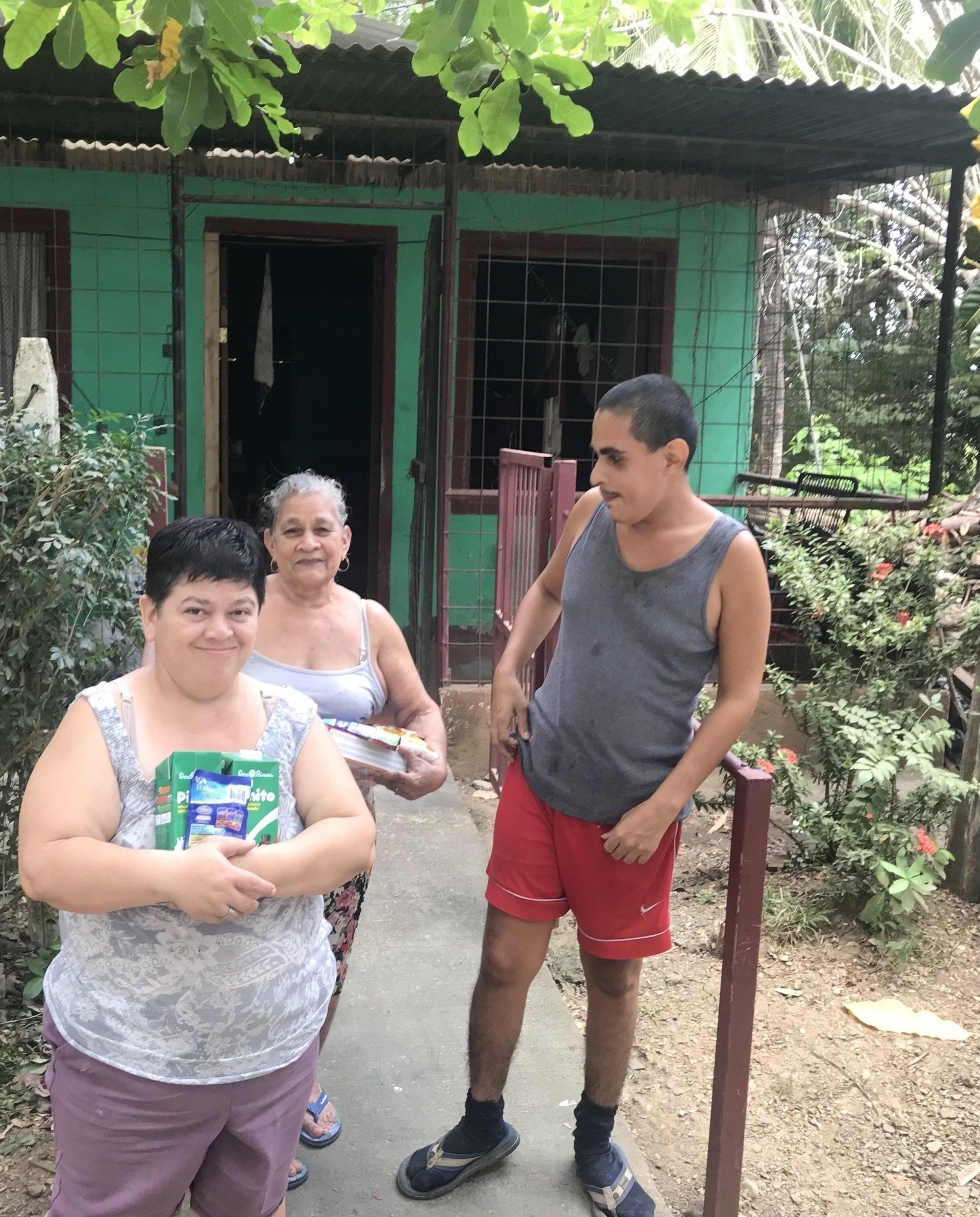 A group of people standing in front of a green house