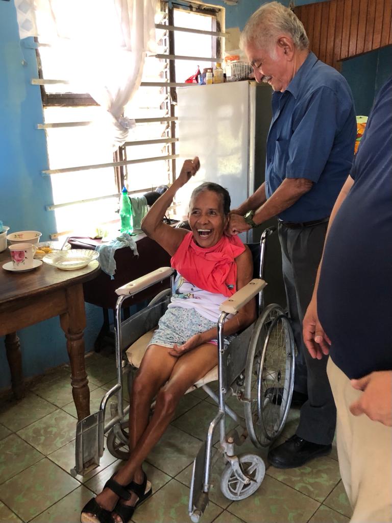 A woman in a wheelchair is laughing while being helped by two men.