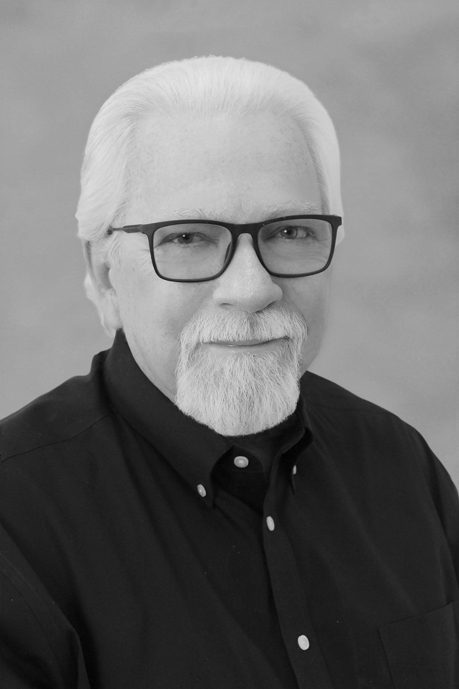 A man with a beard and glasses is wearing a black shirt.