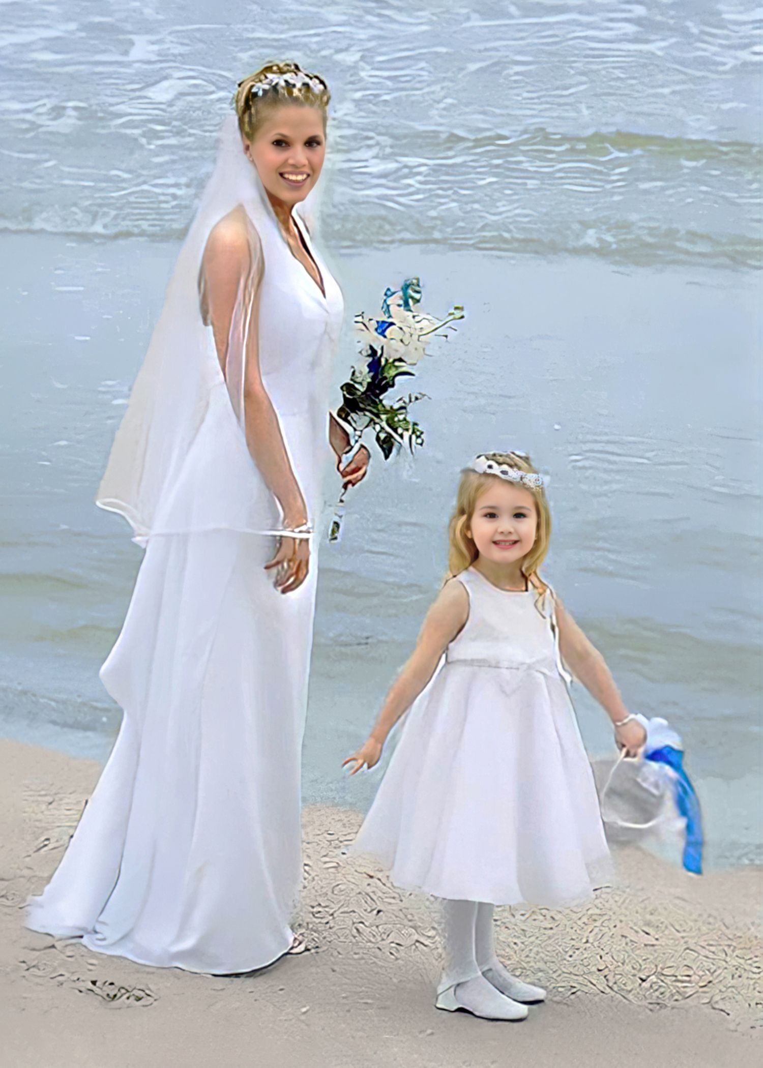 A bride and her flower girl are standing on the beach