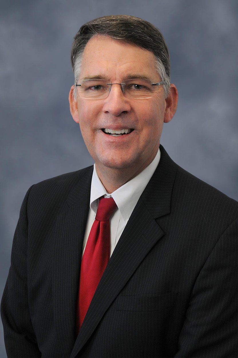 A man in a suit and tie is smiling for the camera