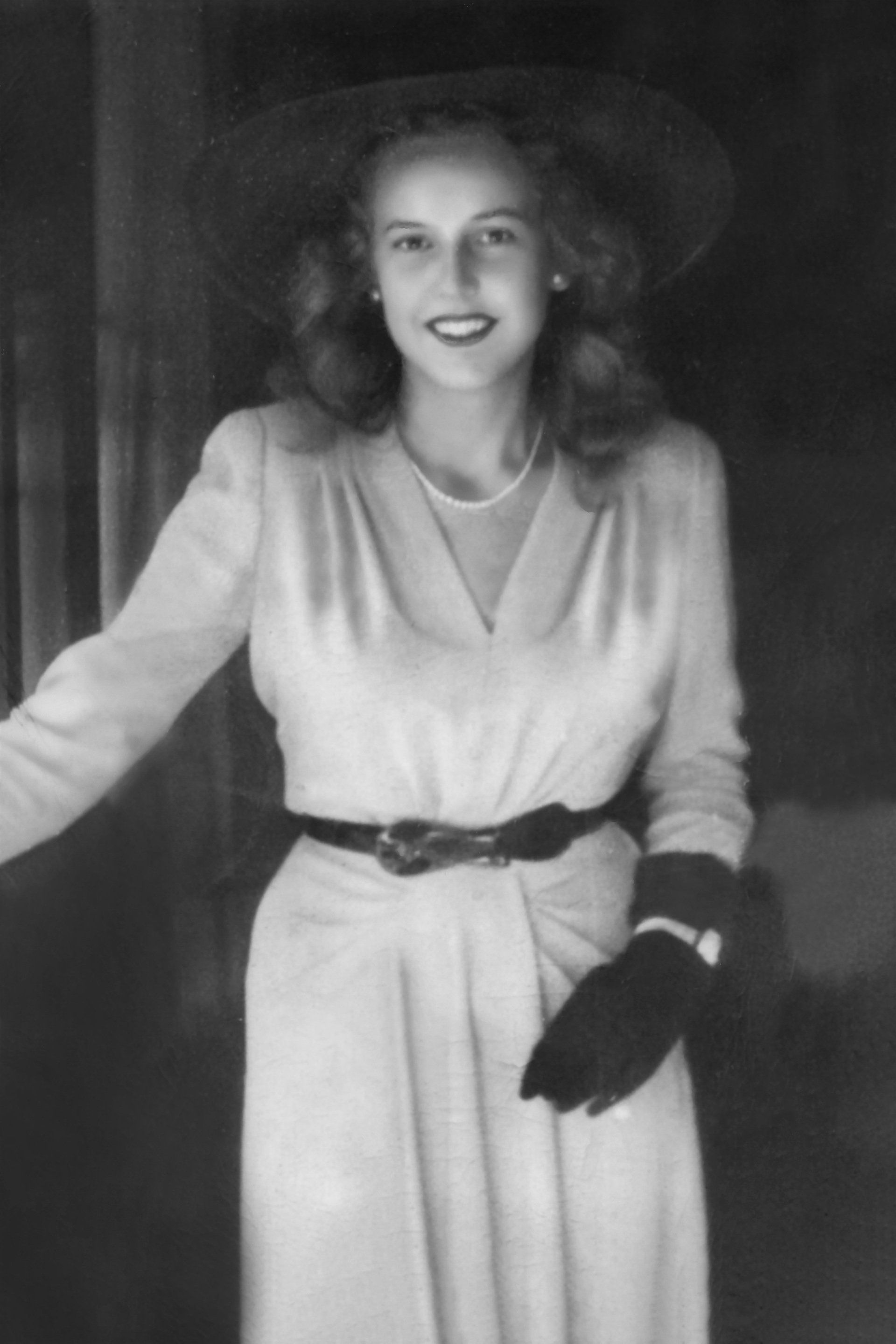 A black and white photo of a woman wearing a hat and gloves