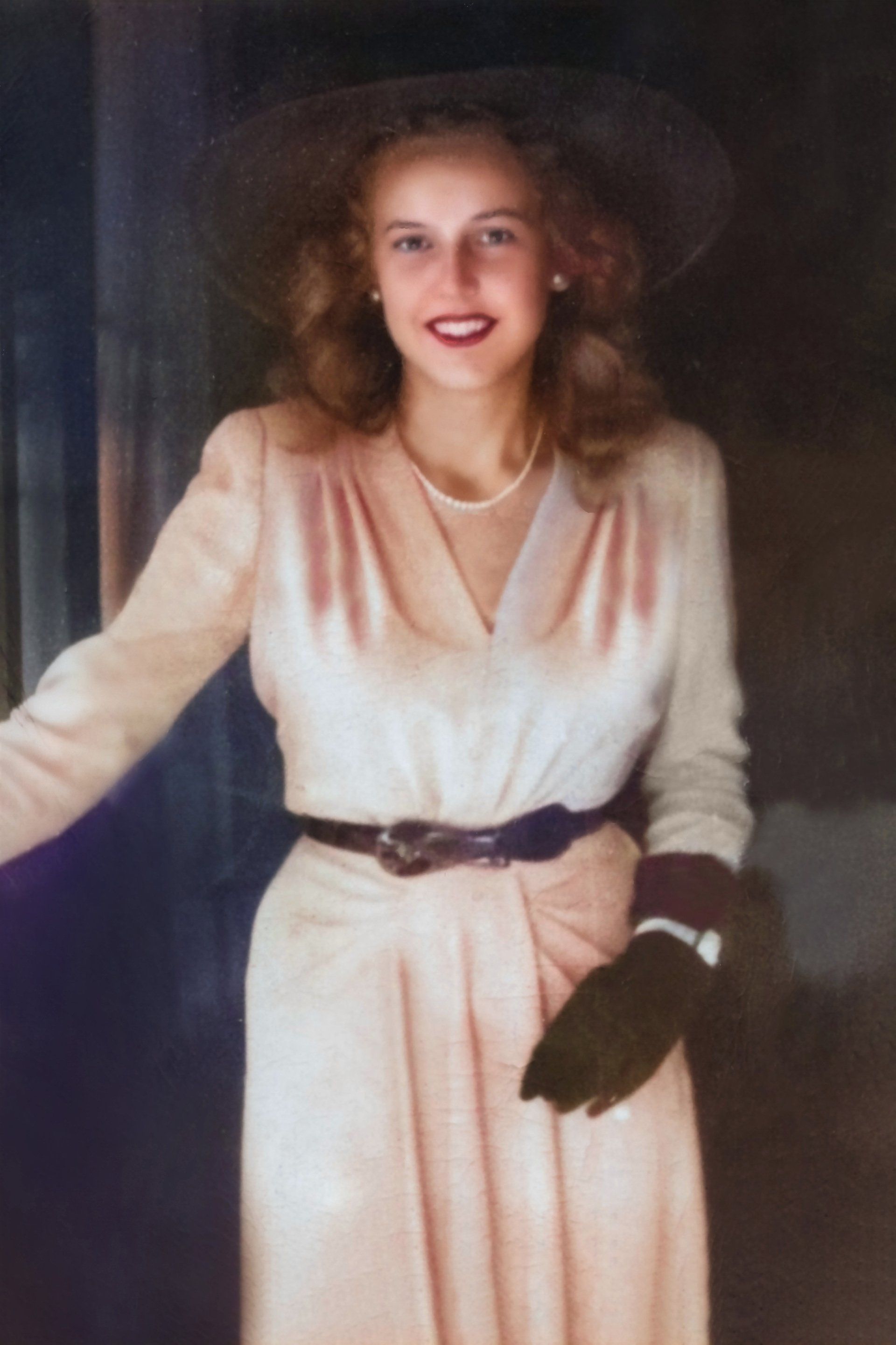 A woman wearing a hat and a dress is smiling