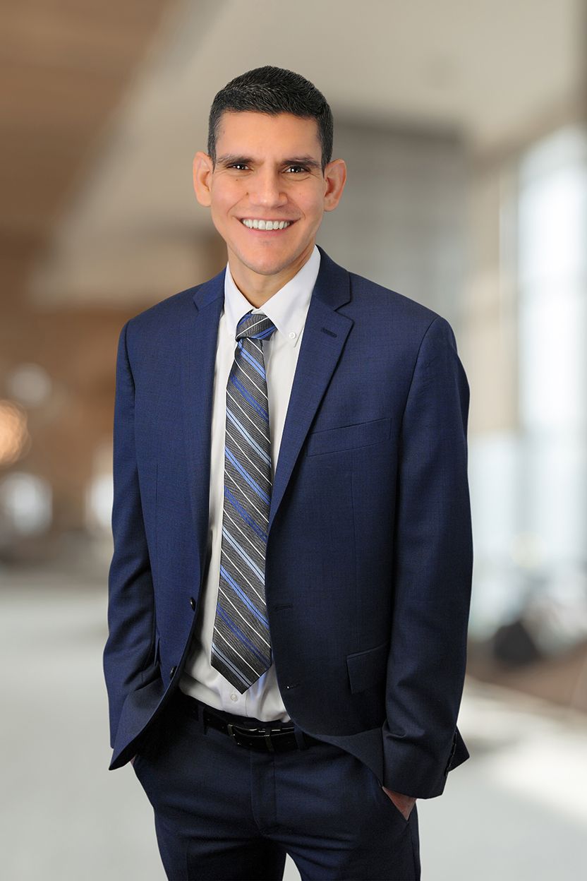 A man in a suit and tie is standing with his hands in his pockets.