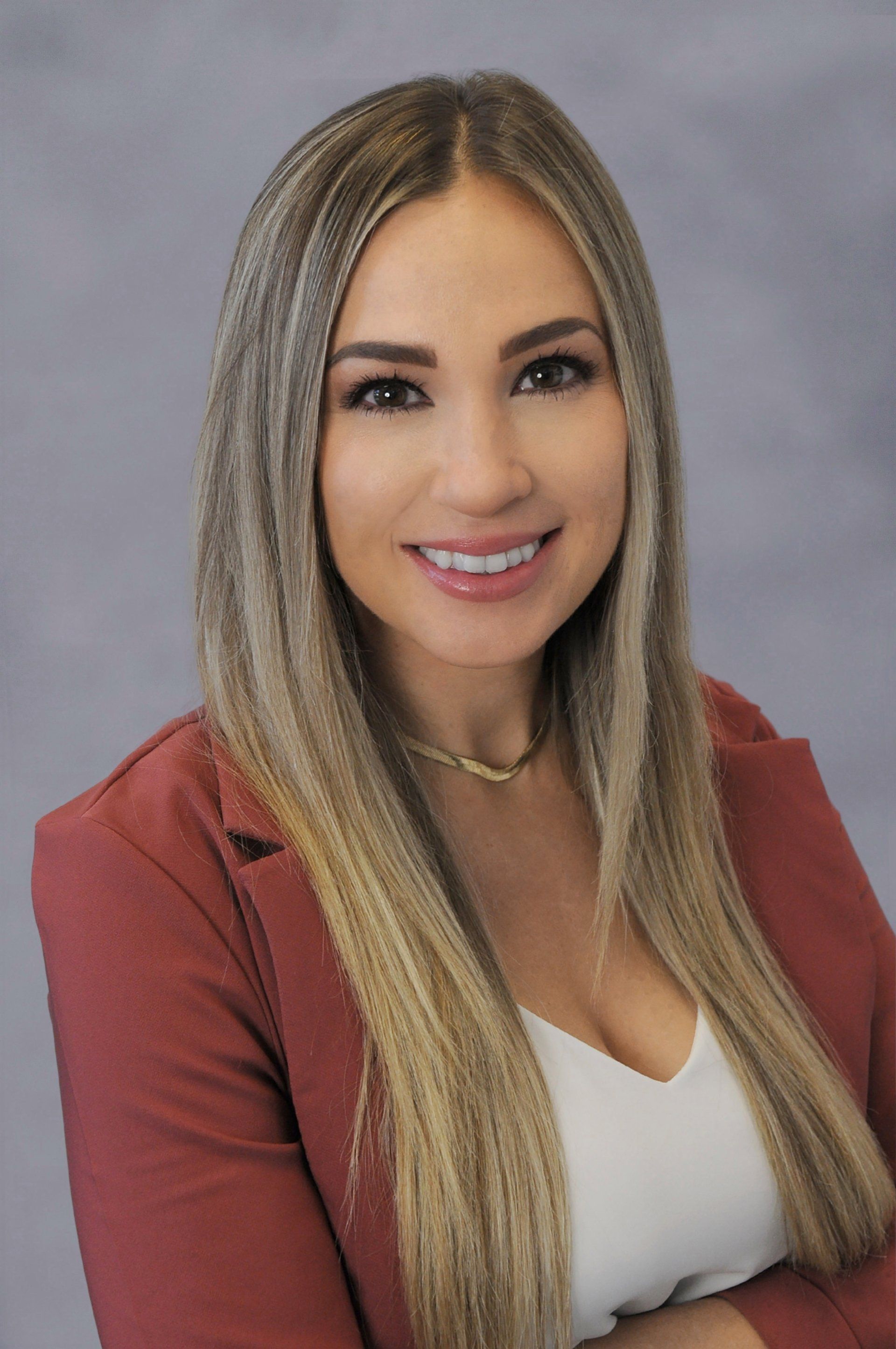 A woman with long blonde hair is wearing a red jacket and a white shirt.