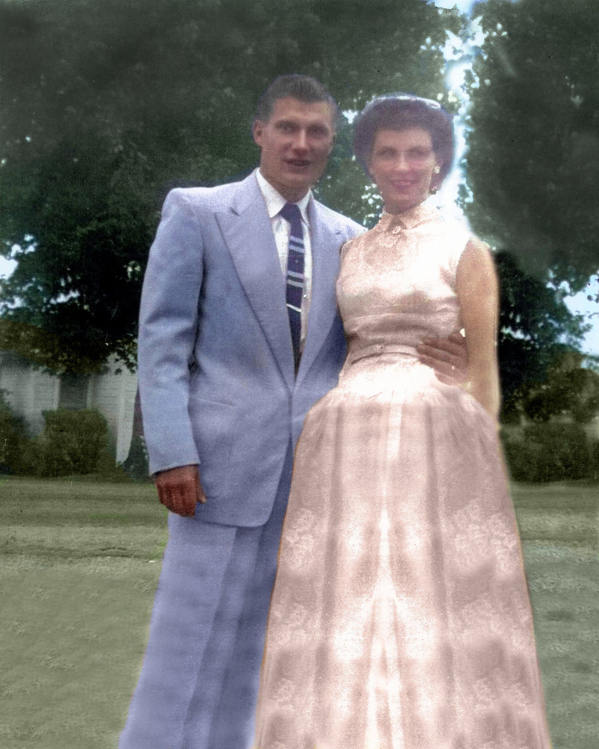 A man in a suit and tie is standing next to a woman in a pink dress.