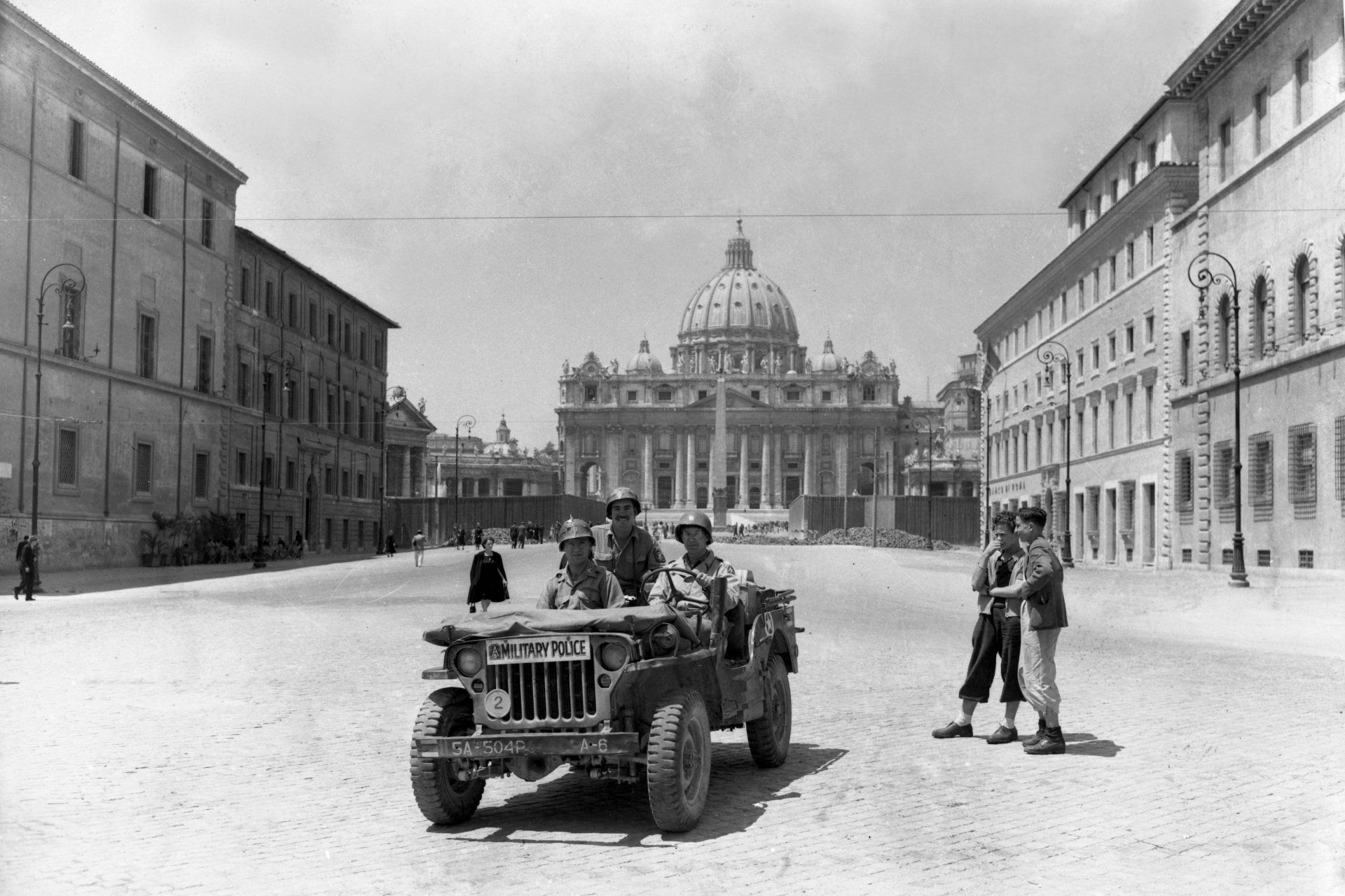 A black and white photo of a jeep driving down a street.