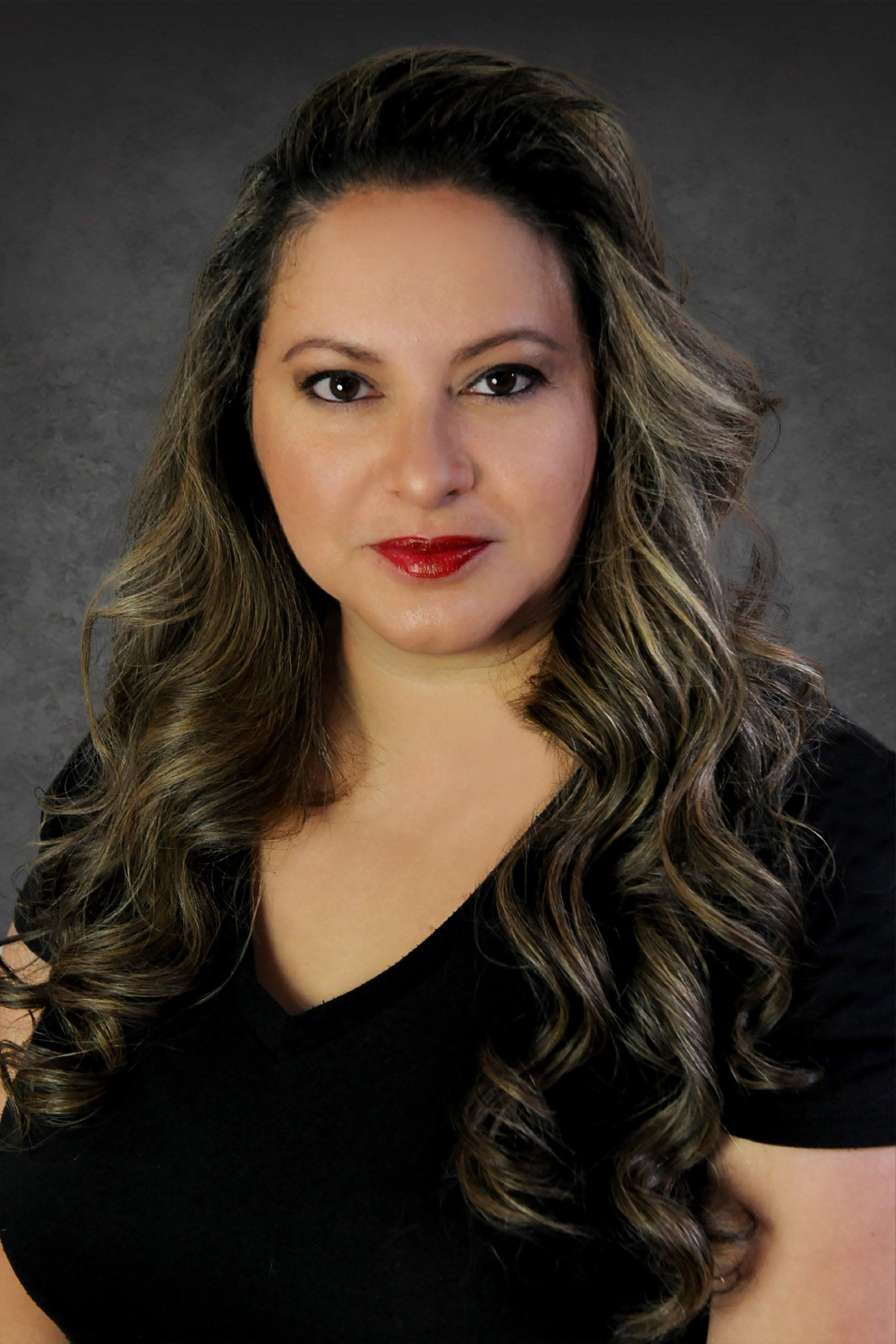 A woman with long hair is wearing a black shirt and red lipstick.