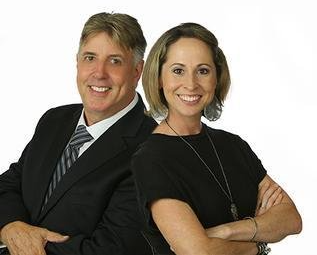 A man and a woman are posing for a picture with their arms crossed.