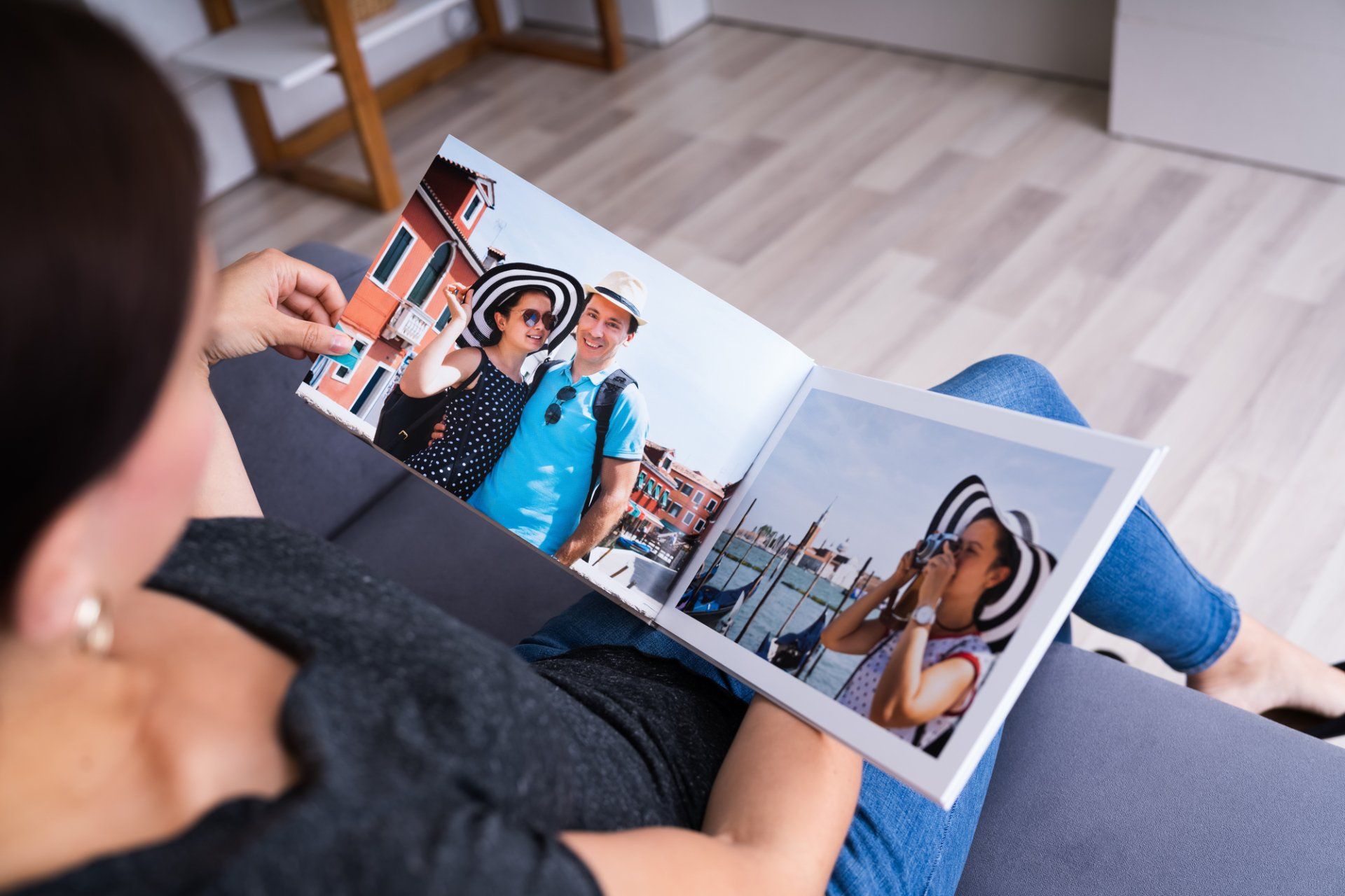A woman is sitting on a couch looking at a photo album.