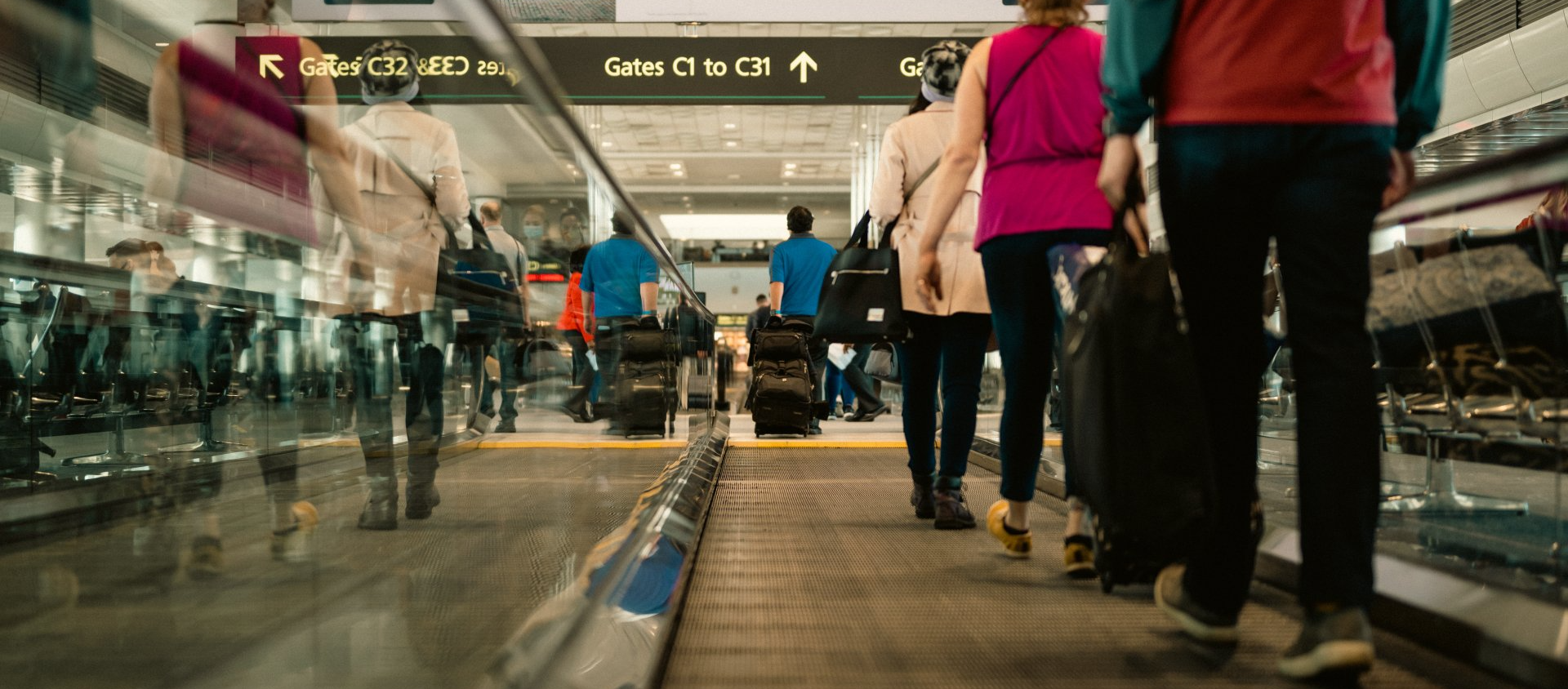 A group of people are walking down an escalator at an airport.