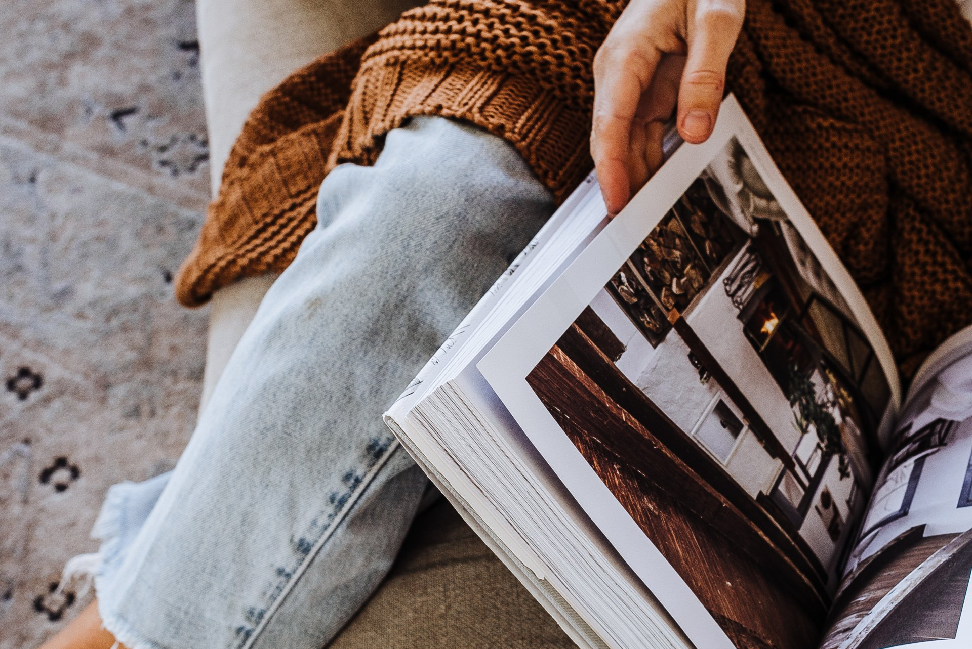 A person is sitting on a couch reading a book.