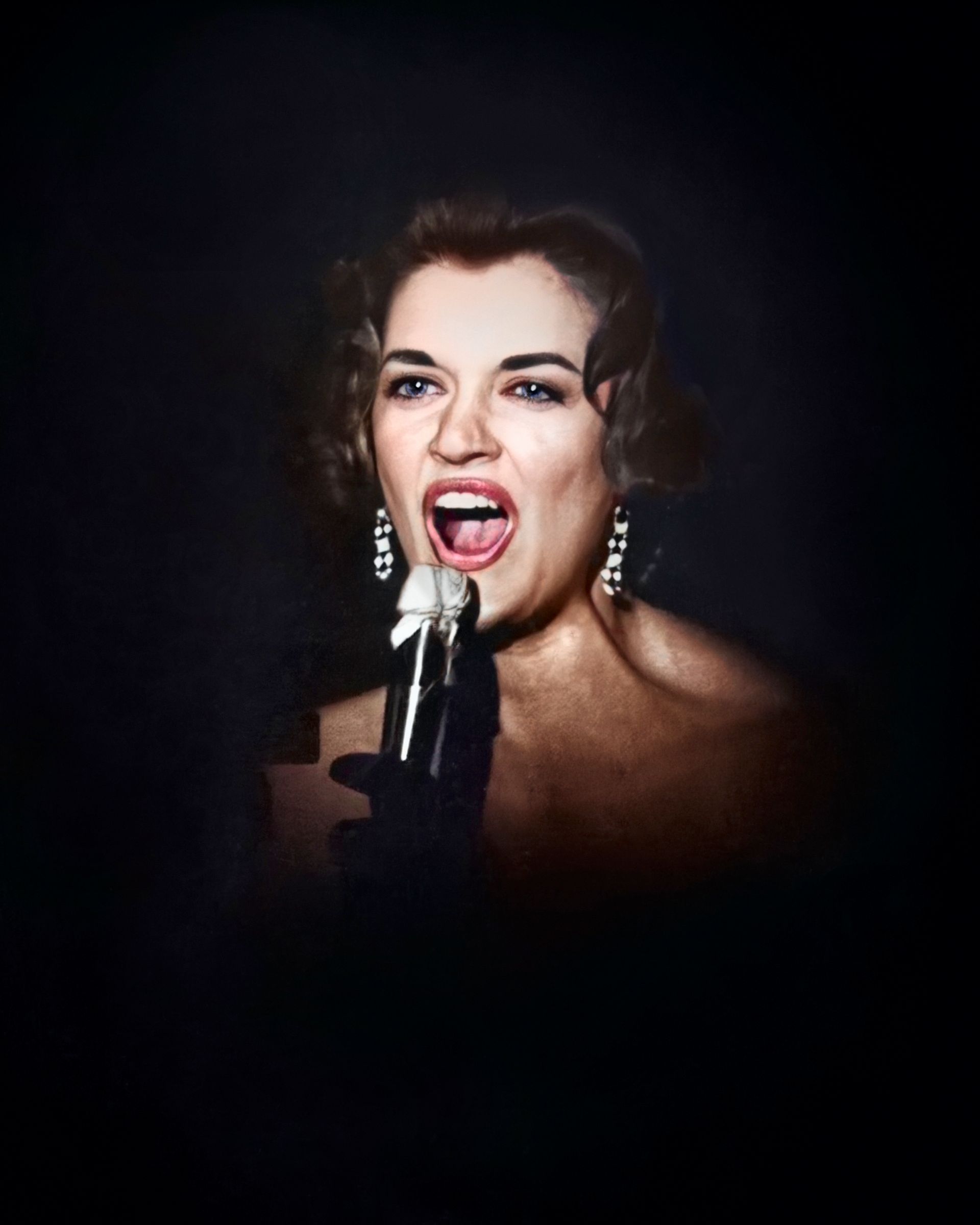 A woman singing into a microphone with her mouth open