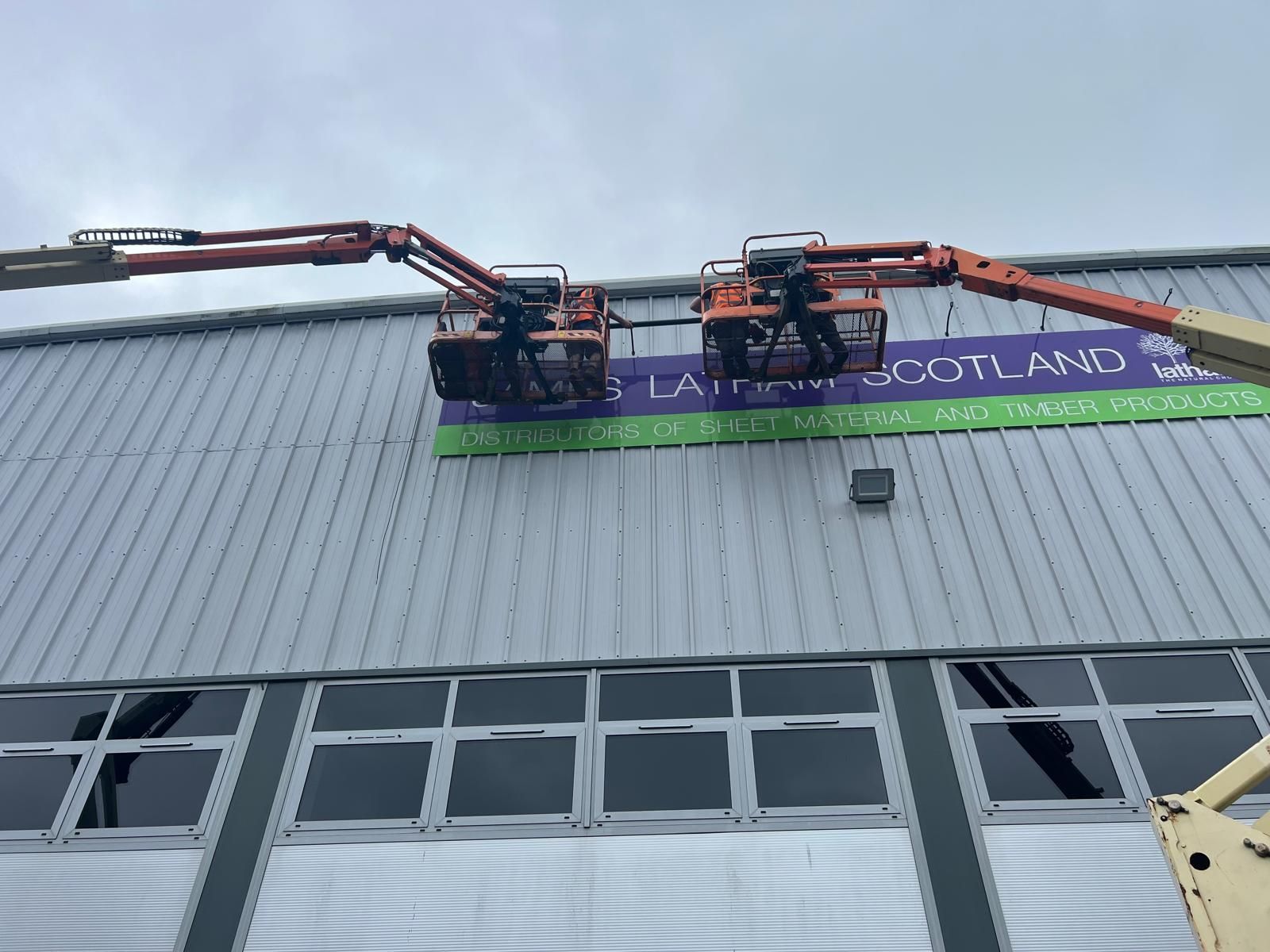 A crane is lifting a sign on the side of a building.