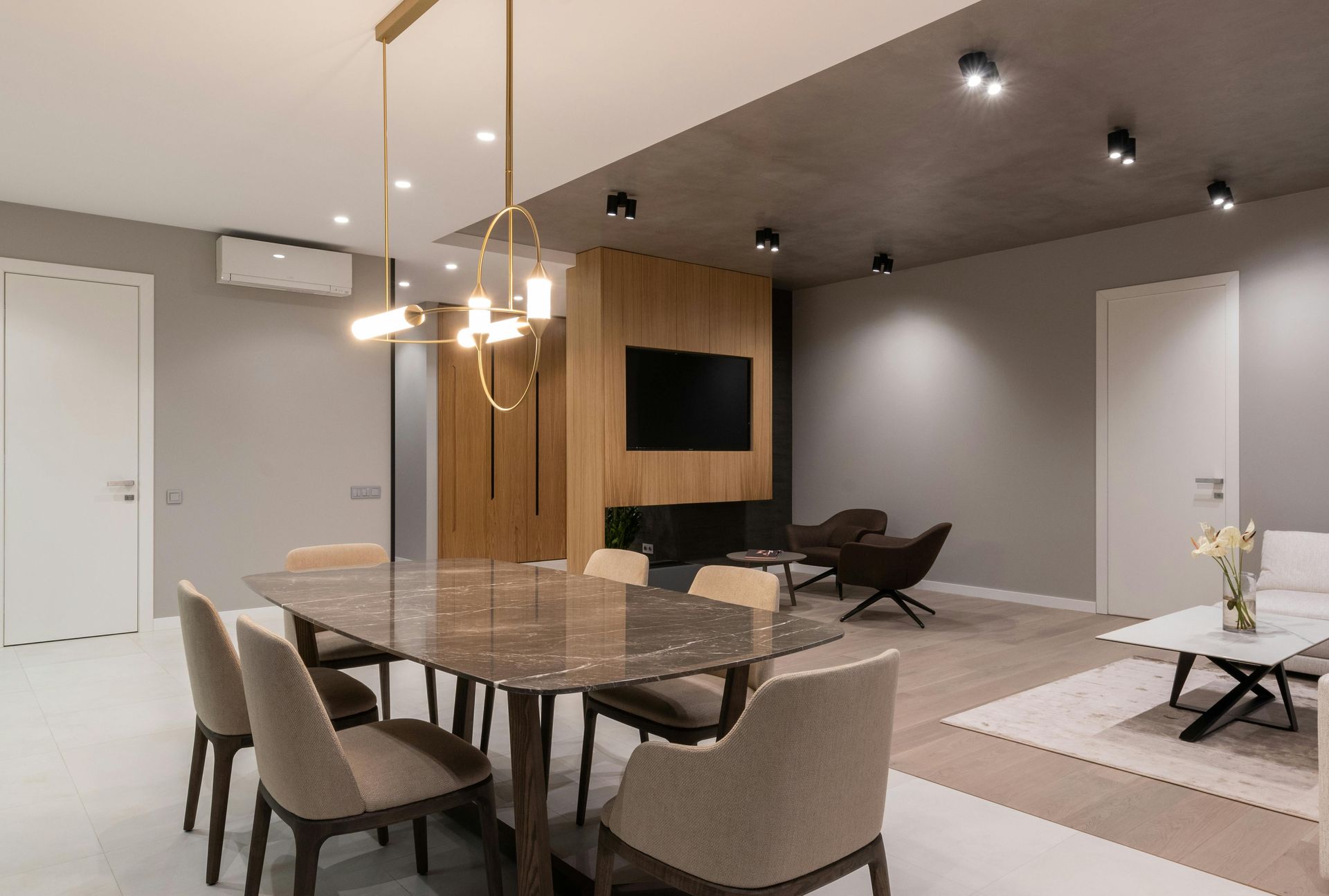 A living room with a dining table and chairs and a television.