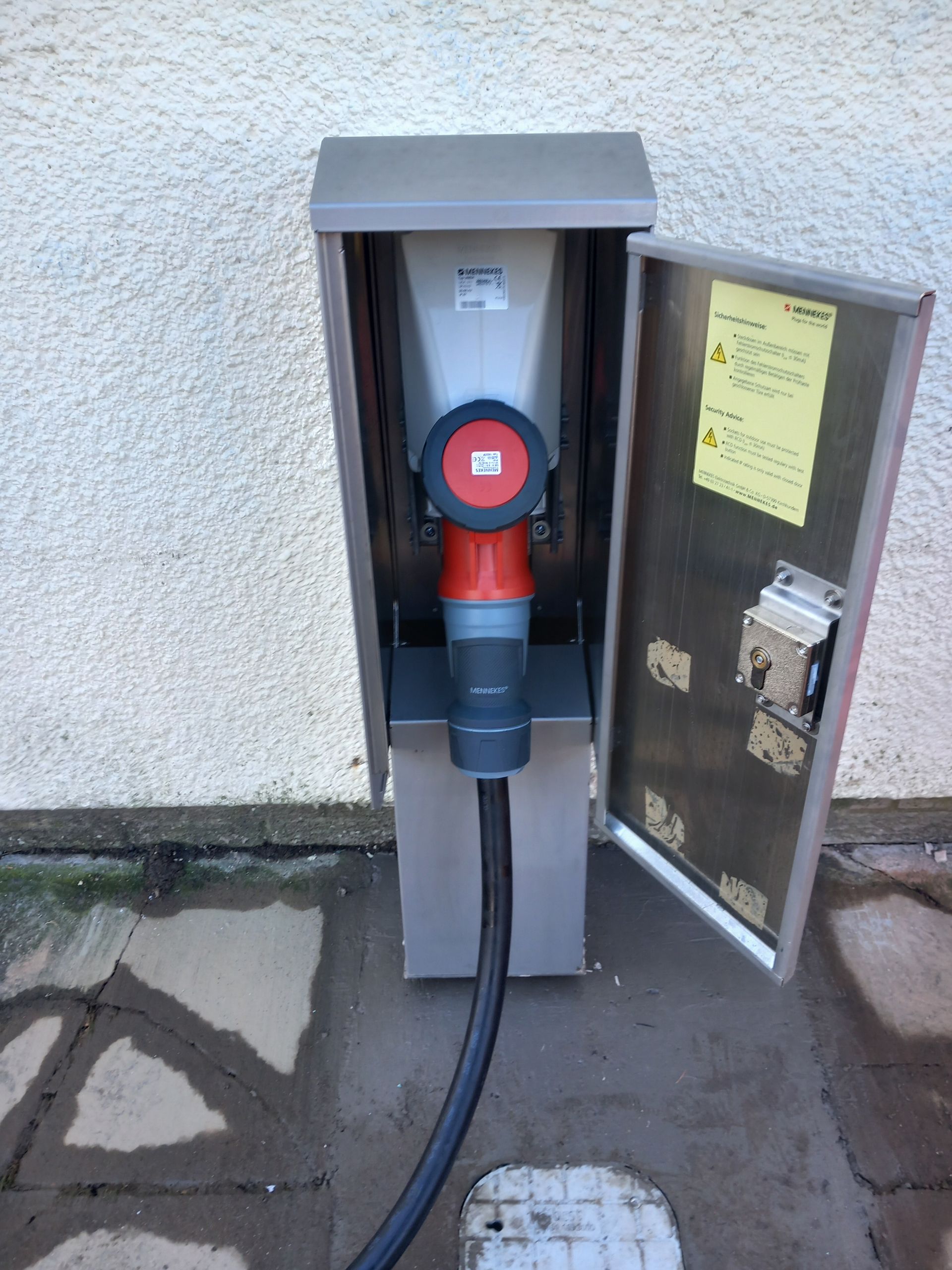 A stainless steel box with a red and black plug in it