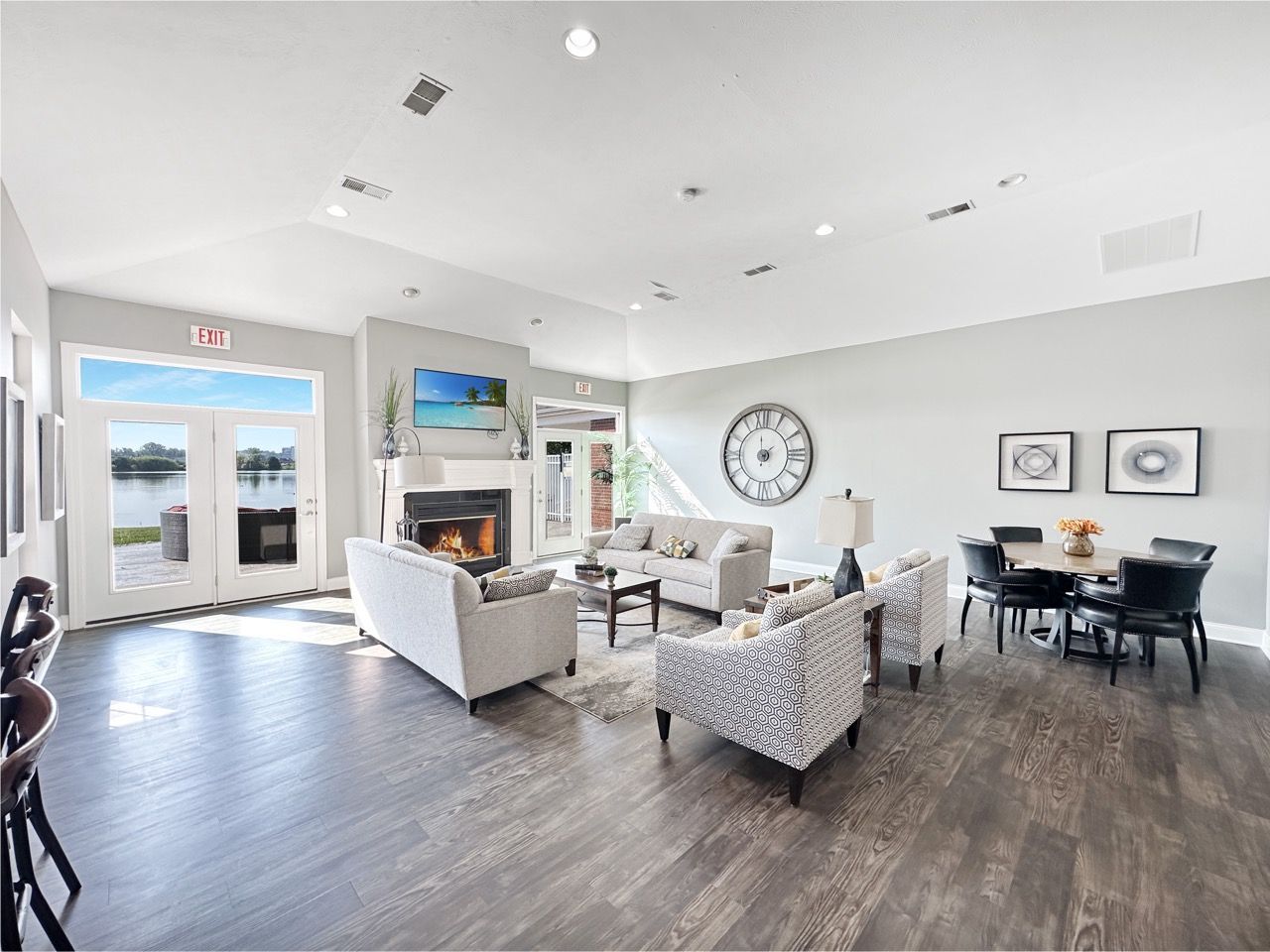 Spacious lounge with fireplace, sofas, dining table, and large windows overlooking a lake.