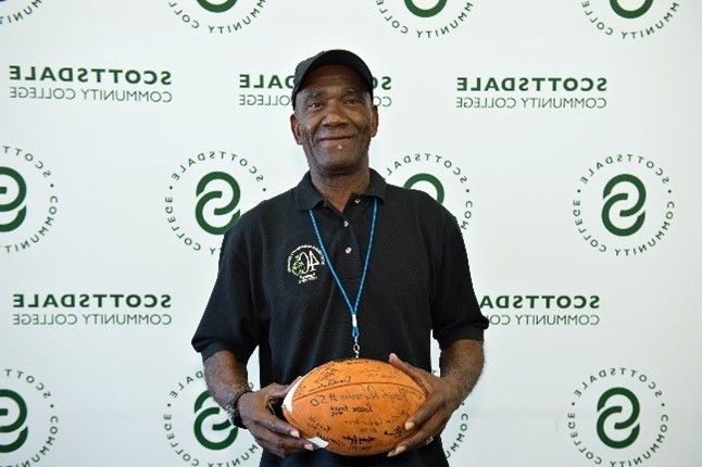 A man is holding a basketball in front of a wall that has the letter e on it
