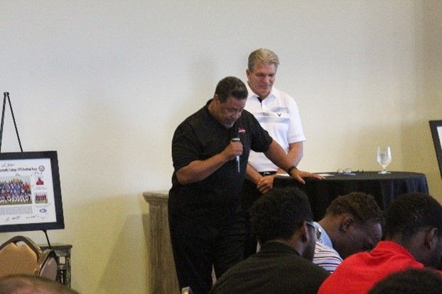 A man speaking into a microphone in front of a group of people