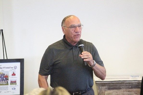 A man is speaking into a microphone in front of a group of people.