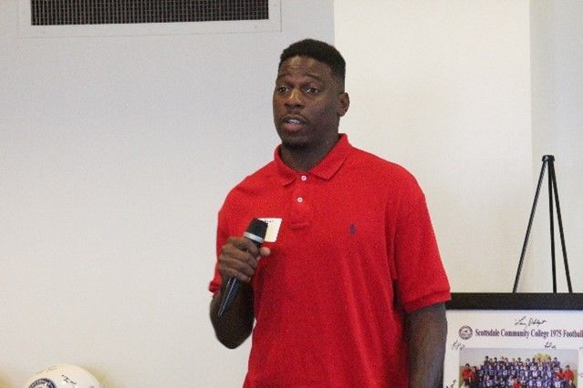 A man in a red polo shirt is holding a microphone.