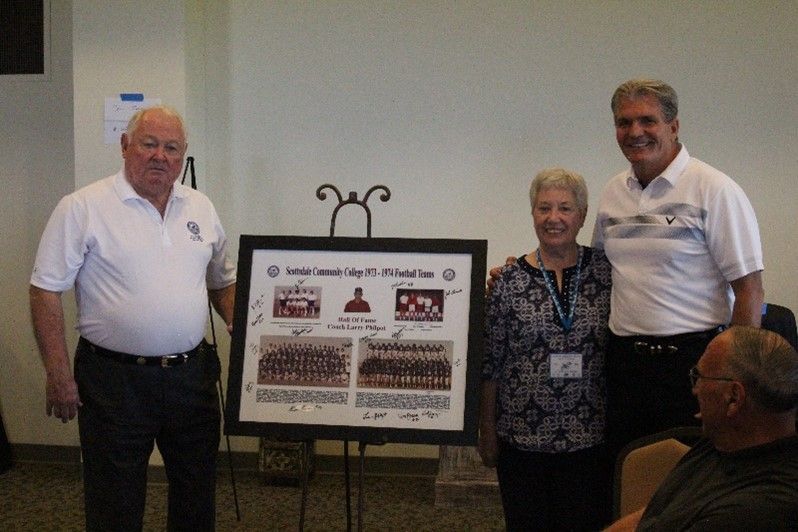 Three people standing next to each other holding a framed picture
