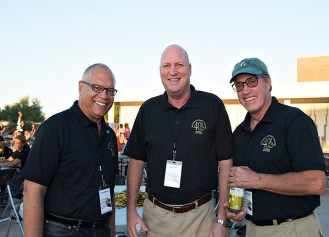 Three men are posing for a picture and one of them is wearing a name tag