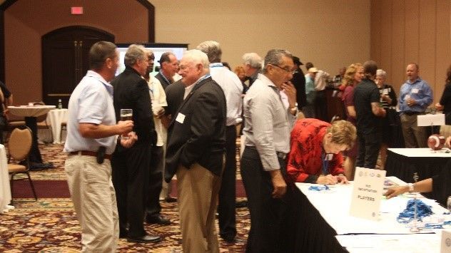 A group of people are standing around tables in a room