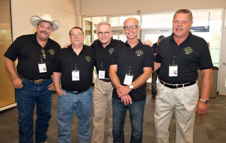 A group of men posing for a picture with one wearing a cowboy hat