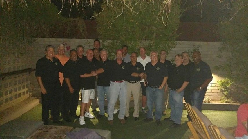 A group of men in black shirts are posing for a picture