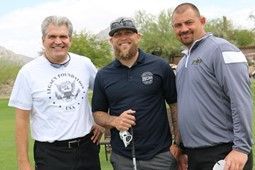 Three men are posing for a picture on a golf course.