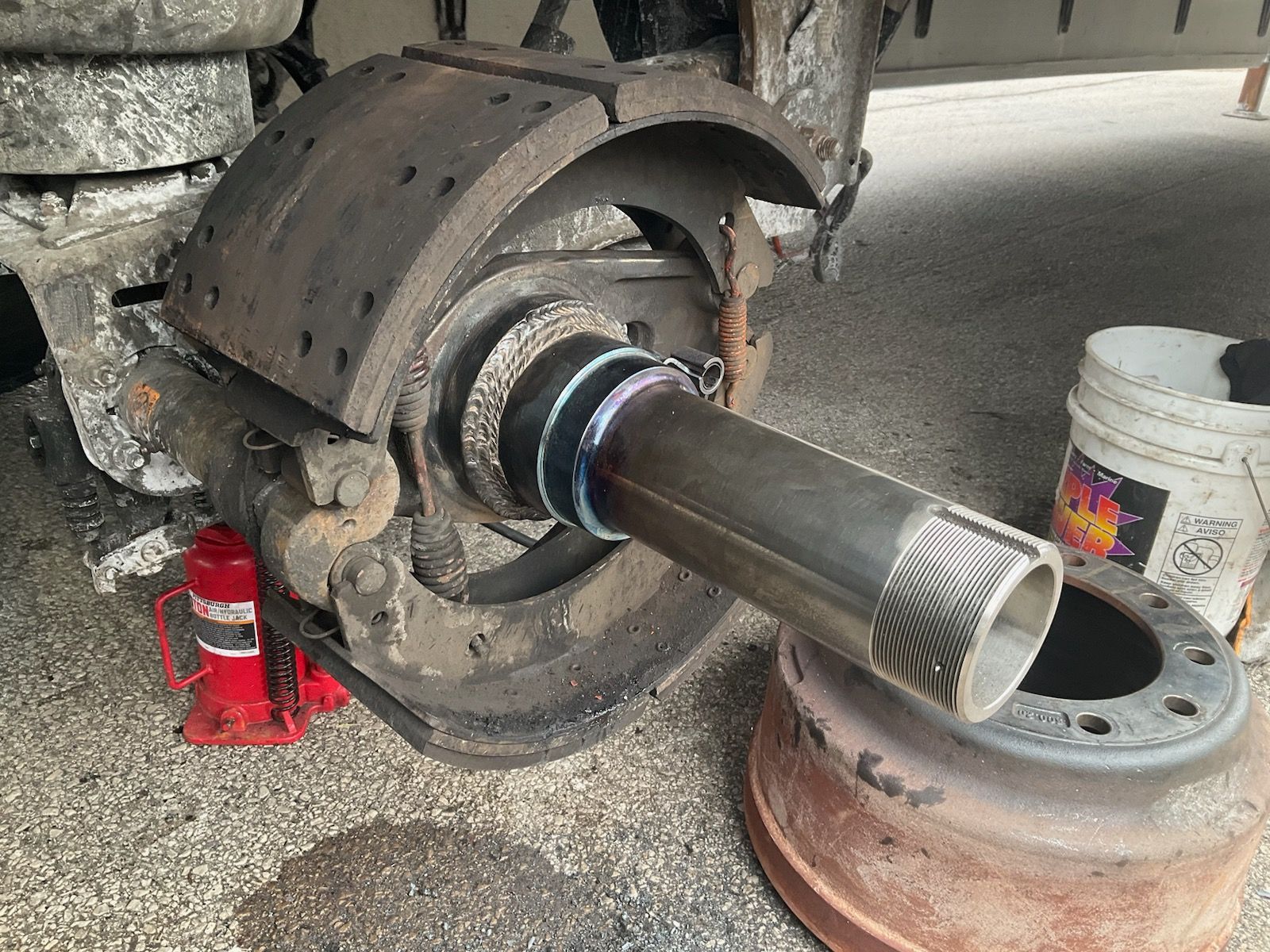 Truck wheel hub with axle shaft and brake assembly, supported by red jack stands in a repair shop