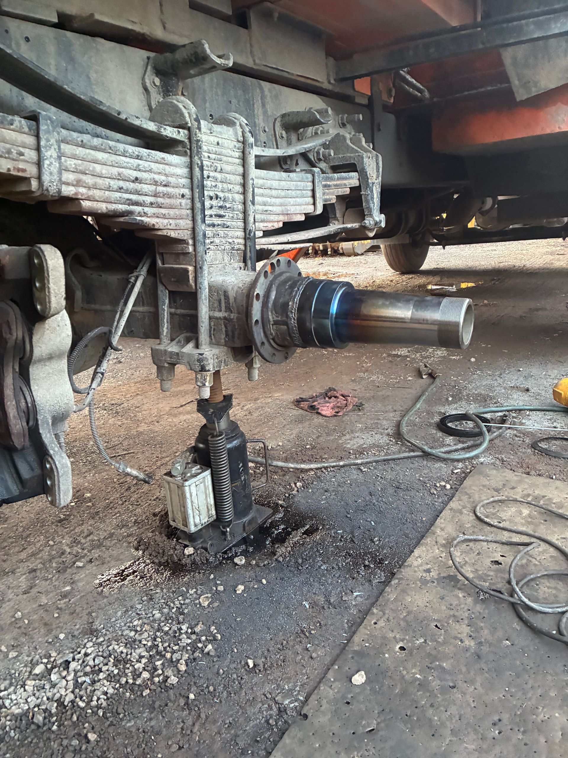 Damaged truck undercarriage with hanging parts and debris on the ground in a garage or workshop