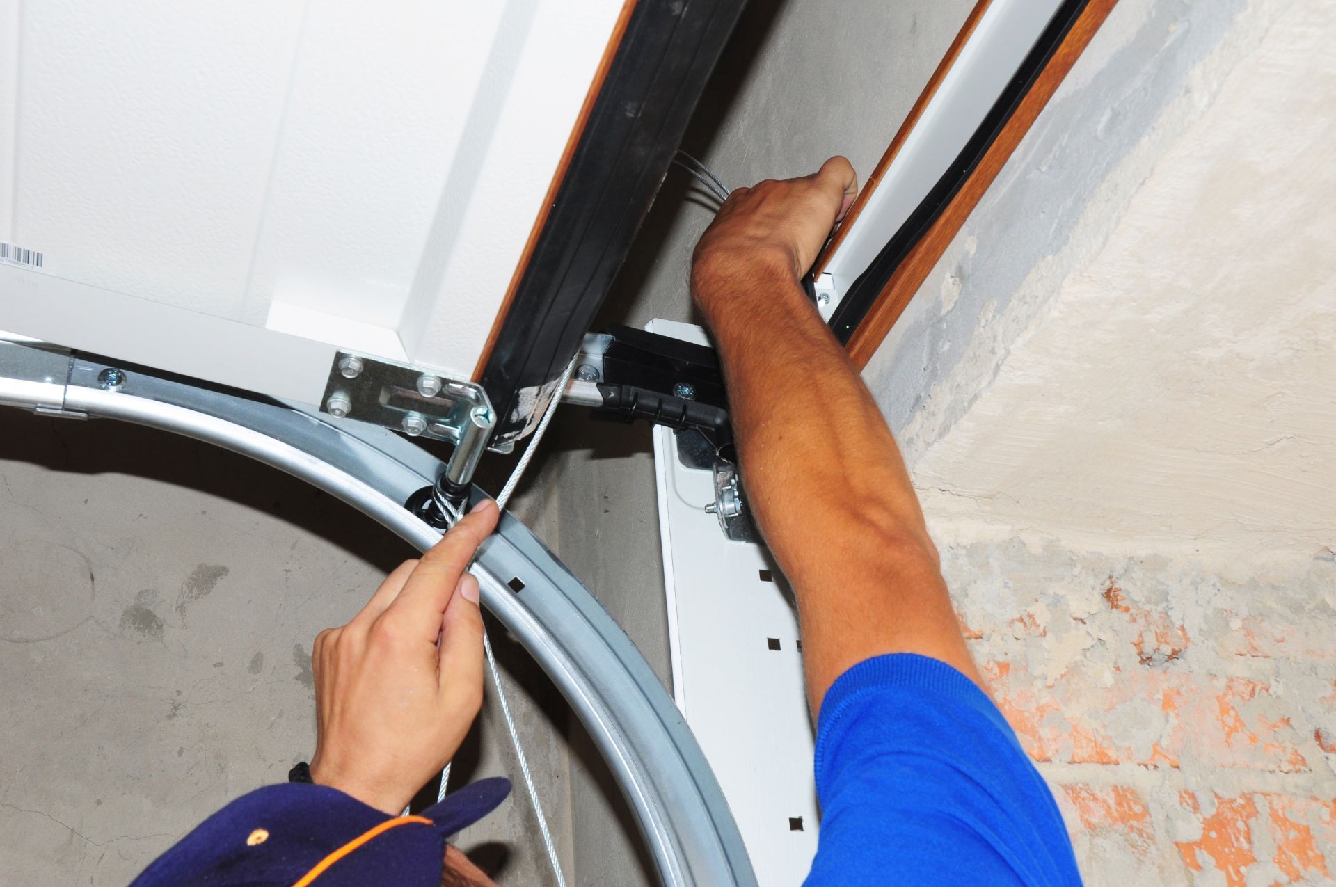 A person using a screwdriver on a garage door mechanism, indoors.