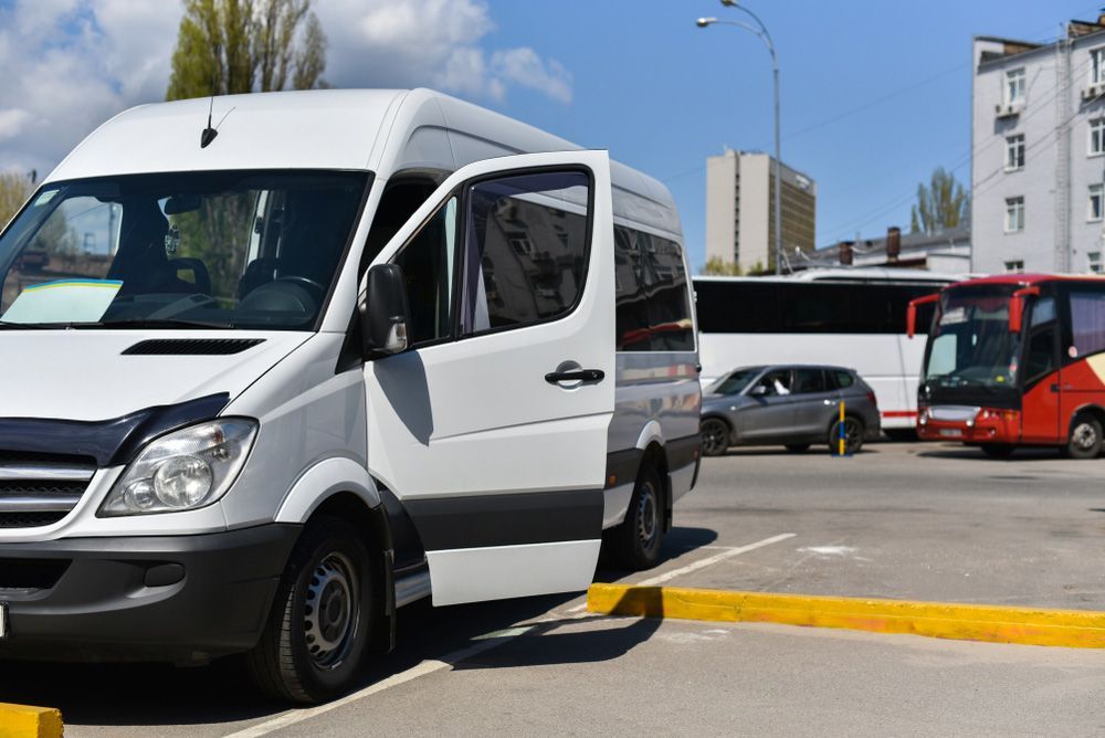 A White Van Is Parked in A Parking Lot Next to A Bus — G & D Ross Bus Charters In Maleny, QLD