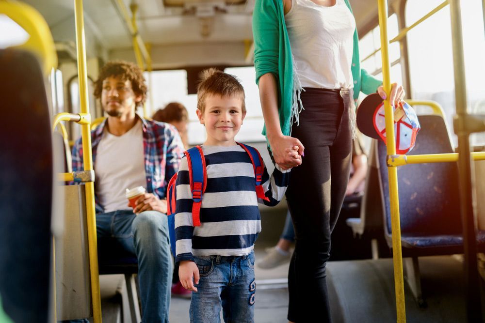A Woman Is Holding a Child 's Hand on A Bus — G & D Ross Bus Charters In Bundaberg, QLD