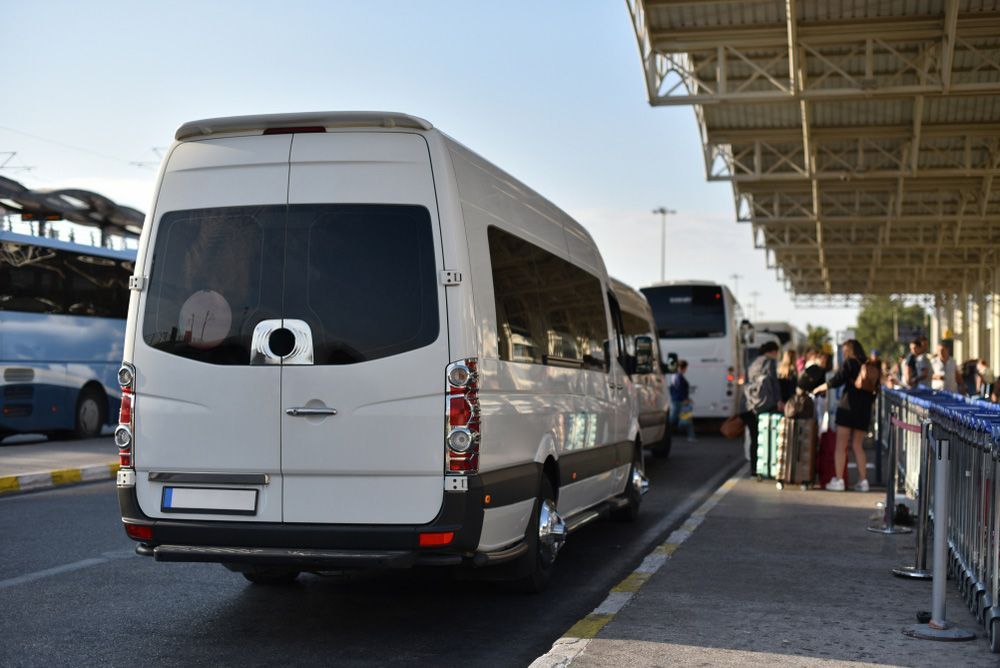 A White Van Is Parked on The Side of The Road at An Airport — G & D Ross Bus Charters In Bundaberg, QLD