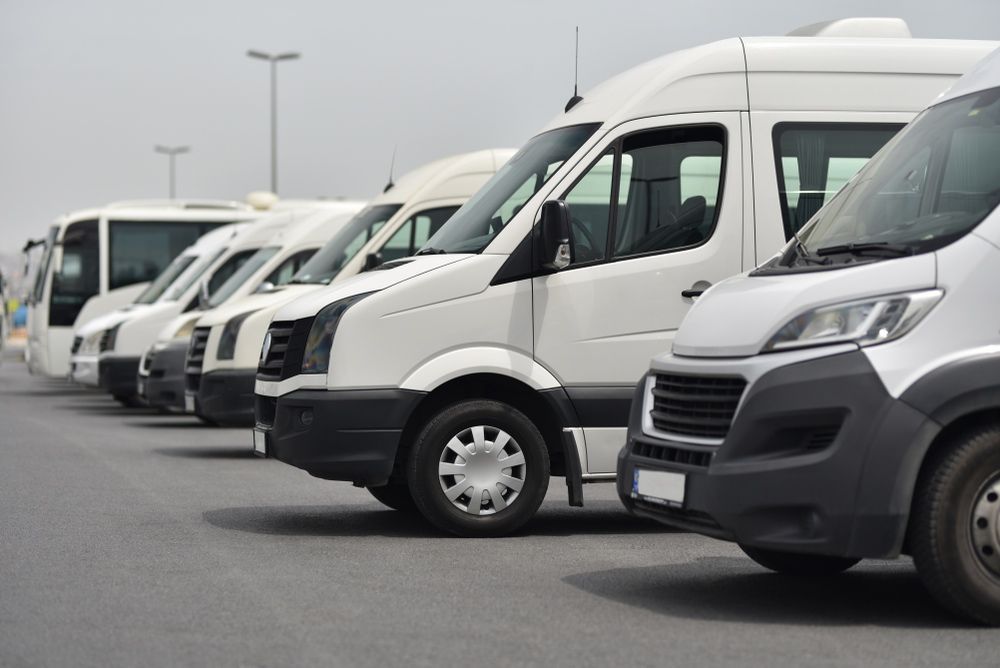 A Row of White Vans Are Parked in A Parking Lot — G & D Ross Bus Charters In Gympie, QLD
