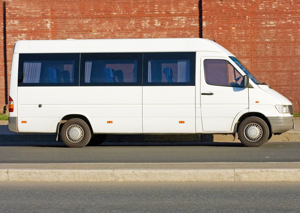 A White Van Is Parked on The Side of The Road in Front of A Brick Wall — G & D Ross Bus Charters In Toowoomba, QLD