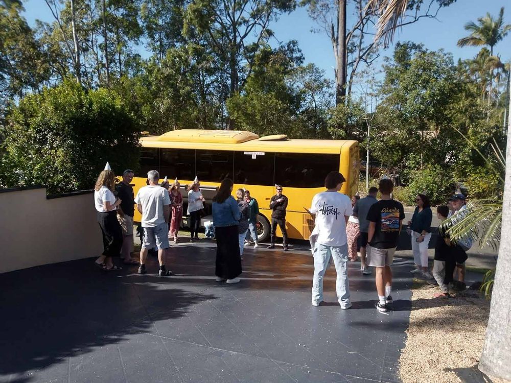 A Group of People Standing in Front of A Yellow Bus — G & D Ross Bus Charters In Magnolia, QLD