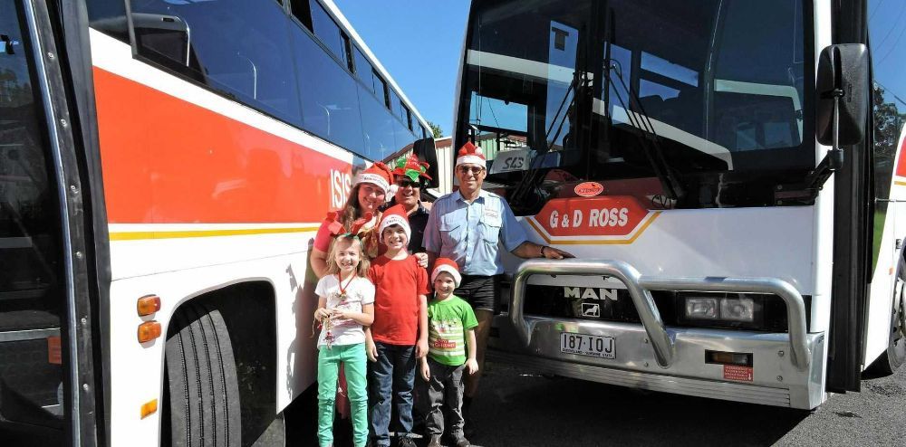 A Group of People Wearing Santa Hats Are Standing in Front of Two Buses — G & D Ross Bus Charters In Bundaberg, QLD