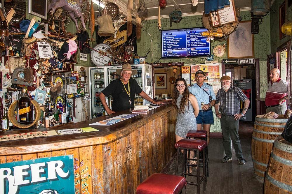 A Group of People Standing in Front of A Bar with A Sign that Says Beer — G & D Ross Bus Charters In Gympie, QLD