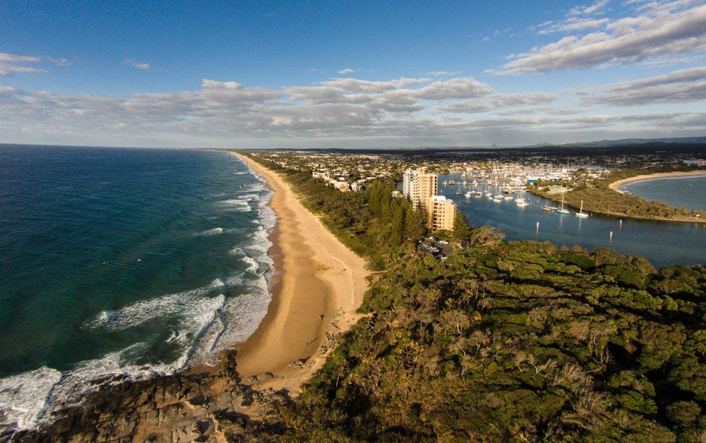 An Aerial View of A Beach Surrounded by Trees and A Body of Water — G & D Ross Bus Charters In Sunshine Coast, QLD