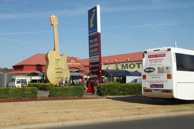 A large guitar statue is in front of a motel