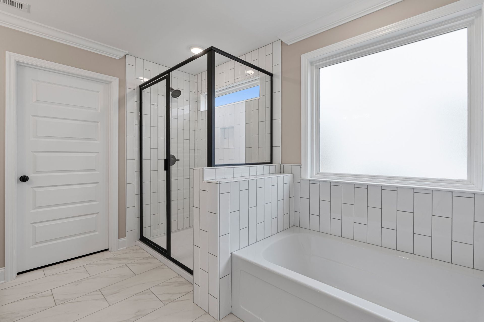 A bathroom with a tub , shower , mirror and window.